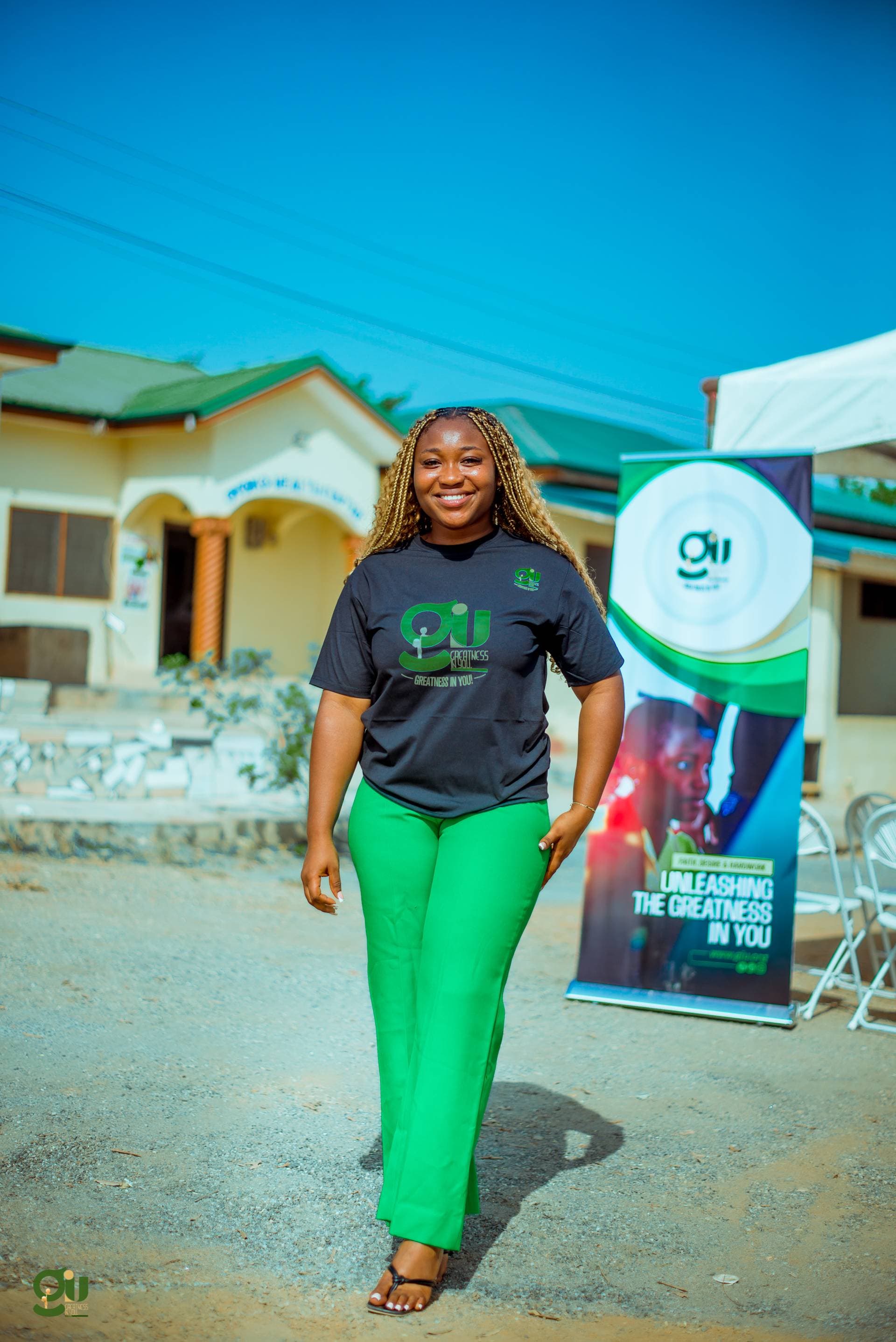 Ama Judith and Kwabena Kesse in GIU branded shirts with GIU banner at community event
