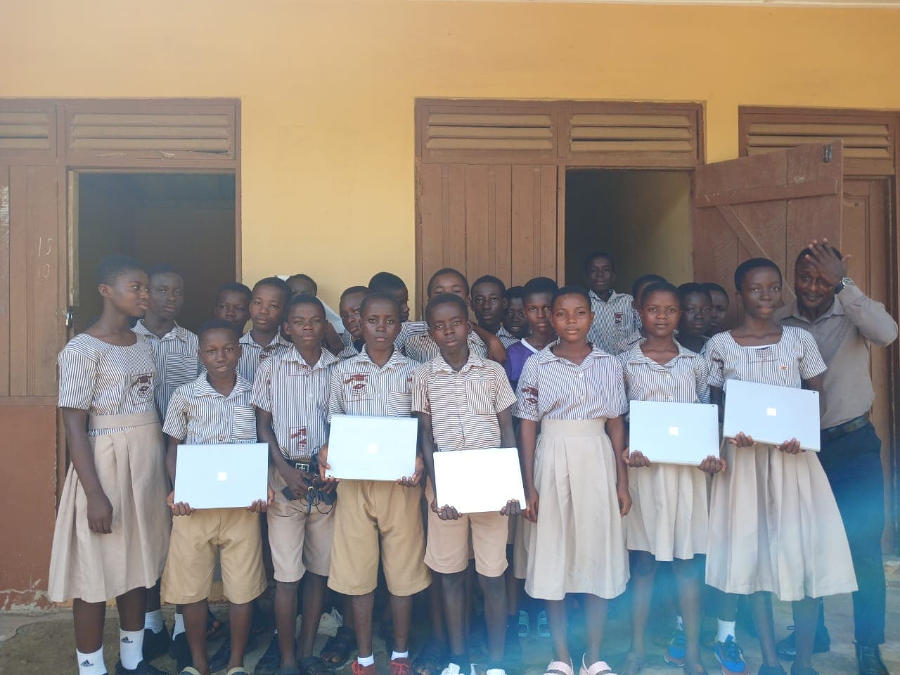 Students proudly holding donated laptops from GIU in Ghana